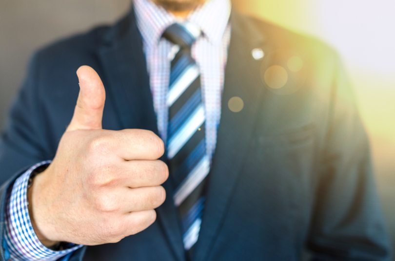 Image of man dressed in suit and giving a thumbs up sign