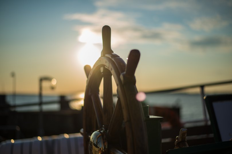 Image of a ship's wheel during sunset.